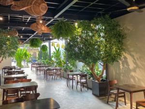 a restaurant with tables and chairs and potted trees at Mong Yen Hotel in Cao Lãnh
