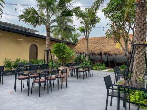 a patio with tables and chairs and palm trees at Mong Yen Hotel in Cao Lãnh