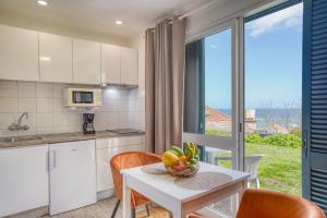 a kitchen with a table with a bowl of fruit on it at Quinta da Vila in Porto da Cruz +21 photos