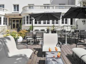 an outdoor patio with tables and chairs and umbrellas at Mercure Paris Saint Cloud Hippodrome in Saint-Cloud