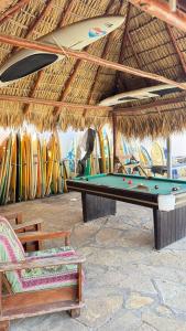 a pool table under a straw roof with surfboards at Casa la barra surf resort in Miramar