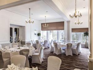 a banquet room with white tables and chairs and chandeliers at Mercure Aberdeen Caledonian Hotel in Aberdeen