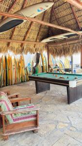 a pool table in a straw hut with surfboards at Casa la barra surf resort in Miramar +11 photos