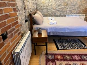 a small bedroom with a bed and a brick wall at Old Balcony in Kutaisi