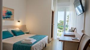 a bedroom with a bed with a desk and a television at Hotel Internazionale in Marotta