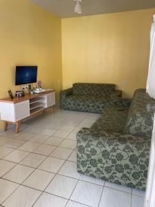 a living room with two couches and a tv at Pousada Mirante do Sol in Piúma