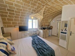 a bedroom with a bed and a stone wall at La Chicca di Fiore - Guest House in Gallipoli +36 photos