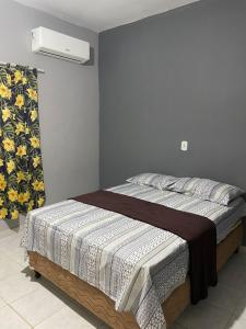 a bedroom with a bed with a blanket on it at Pousada Mirante do Sol in Piúma