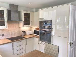 a kitchen with white cabinets and stainless steel appliances at Lakescape in Cirencester