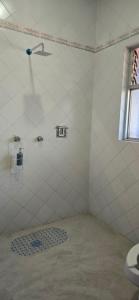 a white tiled bathroom with a shower and a sink at Casa Refugio Budget House 8 Rooms & 9 Bathrooms in Oaxaca City