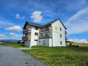a white building with balconies on the side of a road at Apartmány Smrkový vrch in Vaclavov u Bruntalu