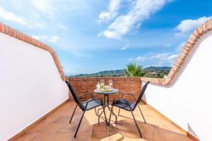 a patio with two chairs and a table on a balcony at Hotel Rural Almazara in Frigiliana
