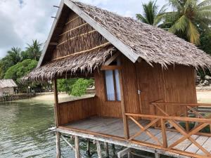 a house on the water with a thatched roof at Nadi awin kamam in Fambemuk +10 photos
