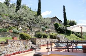 a patio with two chairs and an umbrella next to a stone wall at Tuscany Villa Chianti Hills - Villa Oliveta in Loro Ciuffenna