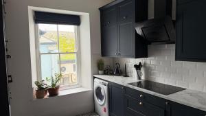 a kitchen with a washing machine and a window at The Teign Rooms in Teignmouth