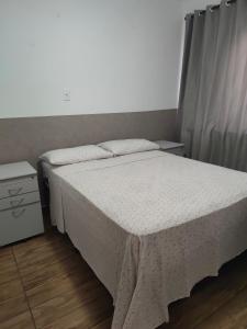 a small bedroom with a bed and a night stand at Apt confortável in Camboriú