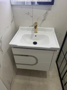 a white bathroom sink with a gold faucet at KEAN Apartments in Vlorë