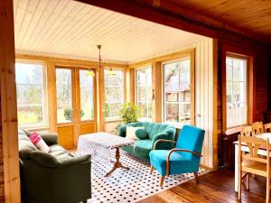 a living room with a couch and chairs and windows at Järve Talu Puhkemaja in Otepää +41 photos