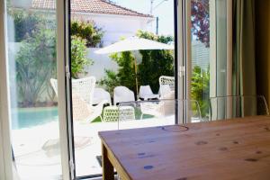 a dining room table with a view of a patio at White and Light House in Costa da Caparica