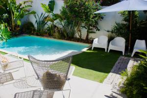 a pool with chairs and an umbrella next to a yard at White and Light House in Costa da Caparica