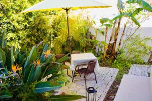 a table and chair under an umbrella in a garden at White and Light House in Costa da Caparica