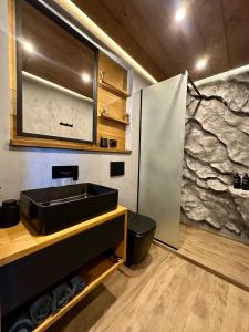 a bathroom with a sink and a stone wall at Шале Ротило in Krivopolʼye