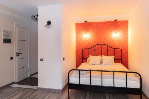 a bedroom with a bed with an orange wall at Park-View Studio Apartment with Free Parking - 10 min to Old Town in Riga
