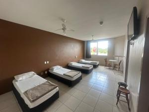 a room with three beds and a table and chairs at Hotel Guaporé - Campo Bom RS in Campo Bom
