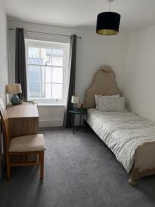 a bedroom with a bed and a chair and a window at The Teign Rooms in Teignmouth