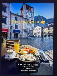 a table with a plate of breakfast food and a clock tower at Casa Antica Druško in Kotor