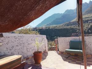 a chair and a plant on a balcony with mountains at Chez Yahia, Au coeur de L'Ourika in Ourika +132 photos