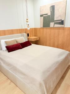 a bedroom with a white bed with a red pillow at Luxury Art Apartment Wrocław in Wrocław
