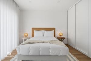 a white bedroom with a large bed and two lamps at Atlantic Apartments in Santa Cruz