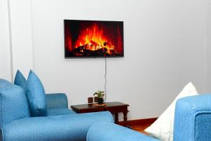 a living room with two blue chairs and a fireplace at Fahari Cedar House in Kericho