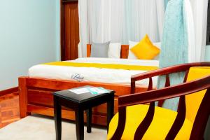 a bedroom with a bed and a chair and a table at Fahari Cedar House in Kericho