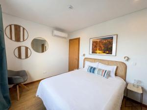 a bedroom with a large white bed and a chair at Pico Island Villas 38 - Private Atlantic Retreat in Santo António