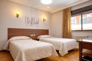 a bedroom with two beds and a window at Hotel Castellano I in Salamanca