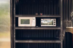 two microwaves are sitting on a shelf at Santa Toro Inn, private rooms close to the beach in Santa Teresa Beach