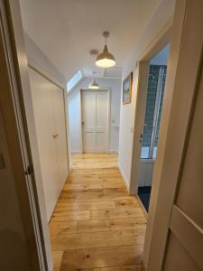 a hallway with a wooden floor and a white door at The Wee Corsee Cosy Coastal Cottage in the Heart of Nairn in Nairn