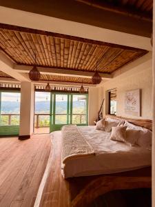 a bedroom with a large bed in a room with windows at Canela Mountain Villa Hotel in Salento