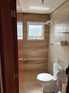 a small bathroom with a toilet and a window at Apto Rio grande com varanda e 160mt de terraço in Rio Grande +26 photos