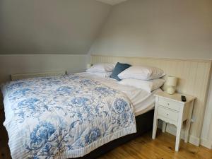 a bedroom with a bed with a blue and white comforter at The Wee Corsee Cosy Coastal Cottage in the Heart of Nairn in Nairn +8 photos
