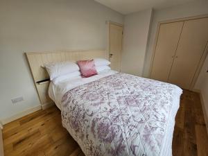 a bedroom with a bed with a pink and white comforter at The Wee Corsee Cosy Coastal Cottage in the Heart of Nairn in Nairn
