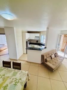 a living room with a couch and a kitchen at Apto Rio grande com varanda e 160mt de terraço in Rio Grande