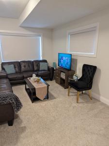 a living room with a couch and a tv at Spacious Luxury walk out Basement in Kitchener