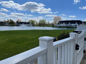 a white fence with a view of a lake at Lakescape in Cirencester