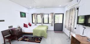 a bedroom with a bed and a desk and a tv at Hestia Homestay- 2 Bedroom Retreat Aymanam in Kottayam