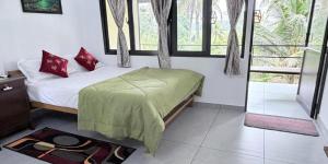 a bedroom with a bed with a green blanket on it at Hestia Homestay- 2 Bedroom Retreat Aymanam in Kottayam