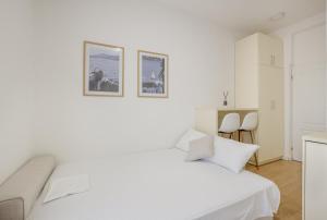a white bedroom with a bed and two pictures on the wall at Sea Point Apartments Igalo in Igalo