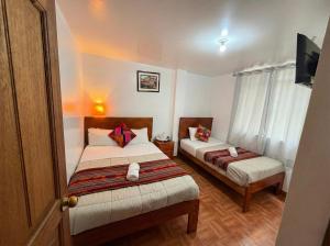 a hotel room with two beds and a tv at Machu Picchu Sacred Valley in Machu Picchu +4 photos